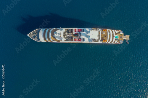 Top down aerial image large holiday cruise ship in the middle of the ocean with the small speed boat across around.