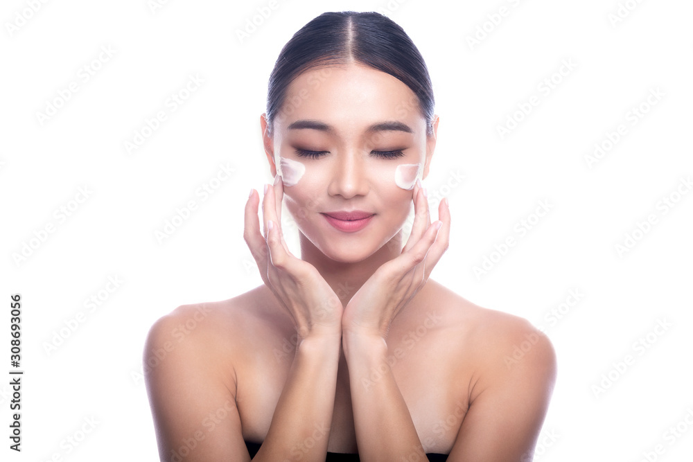 Beautiful Young Asian Woman with Clean Fresh Skin isolate on white background. Spa, Face care, Facial treatment, Beauty and Cosmetics concept. Cream on face, finger touch, eye close, smile.