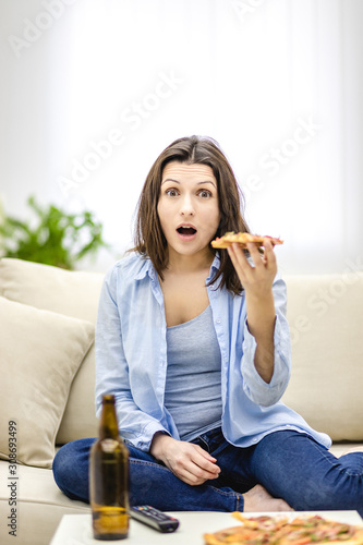 Brunette woman is shocked of TV show. She opens her mouth.