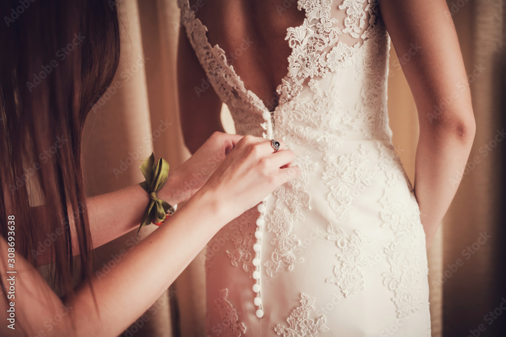 Gorgeous, bride in white dress, preparing for the wedding. Woman puts on a dress.