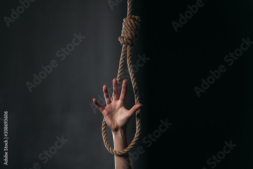 partial with of female hand in hanging rope noose on black background