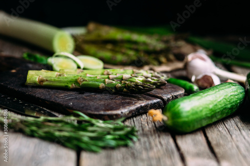Green raw asparagus and green fresh vegetables on a wooden table