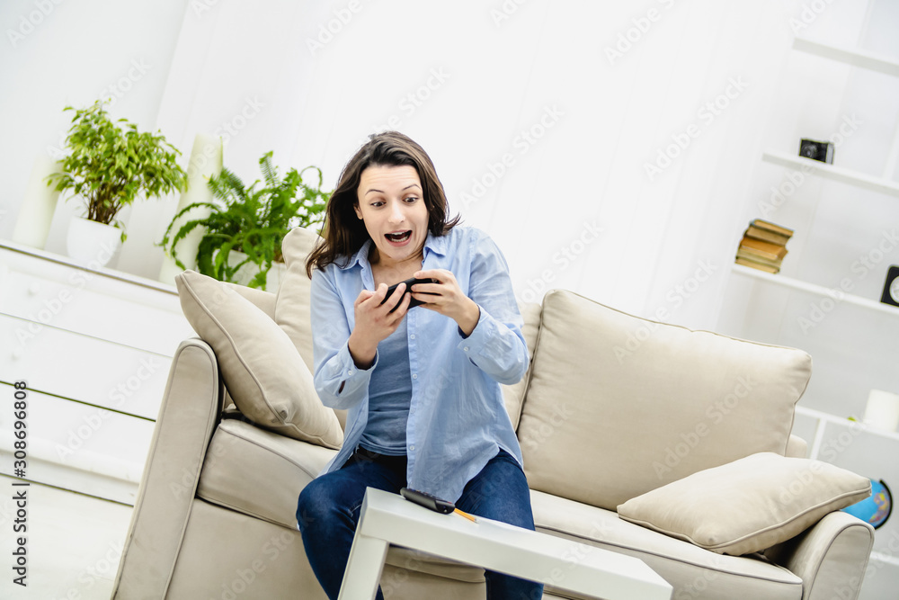 Attractive brunette woman is involved in phone game. She is trying to pass the level. Copy space. Attractive brunette woman is involved in phone game. She is trying to pass the level. Copy space.