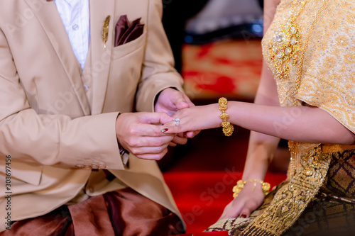 Wedding rings. He Put the Wedding Ring on Her. Close up Groom Put the Ring on bride. thai wedding ceremony and thai wedding decoration.