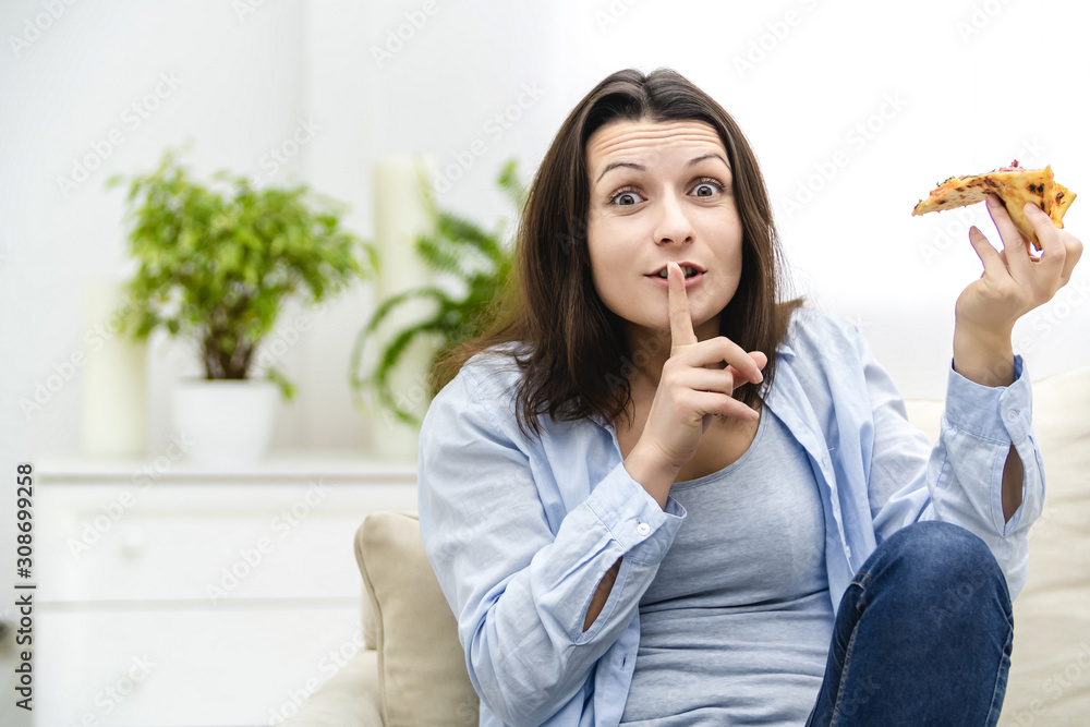 Beautiful young woman wants to eat pepperoni pizza slice so bad. But, she is on diet. So, she makes a silent gesture, for nobody to find out about her cheat. Beautiful young woman wants to eat pepperoni pizza slice so bad. But, she is on diet. So, she makes a silent gesture, for nobody to find out about her cheat.