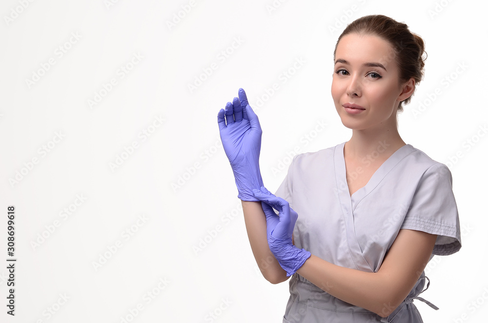 Beautiful female doctor, medical assistant or nurse putting on latex or rubber gloves on white background. Health care concept. Copy space for your text Beautiful female doctor, medical assistant or nurse putting on latex or rubber gloves on white background. Health care concept. Copy space for your text