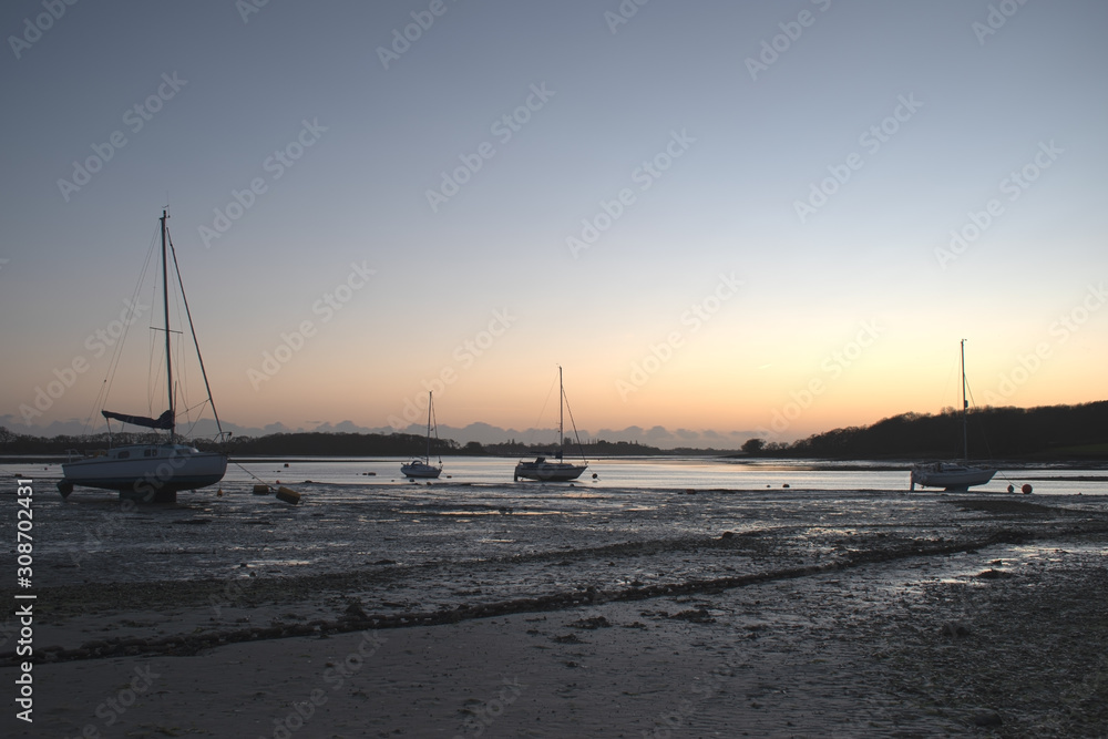 Sunset at Dell Quay sailing club near Chichester. Sun setting in a blaze of colours and reflecting of the water and sand at low tide.