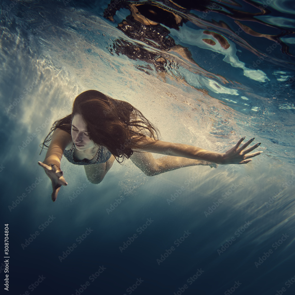 A girl in a brilliant suit swims underwater