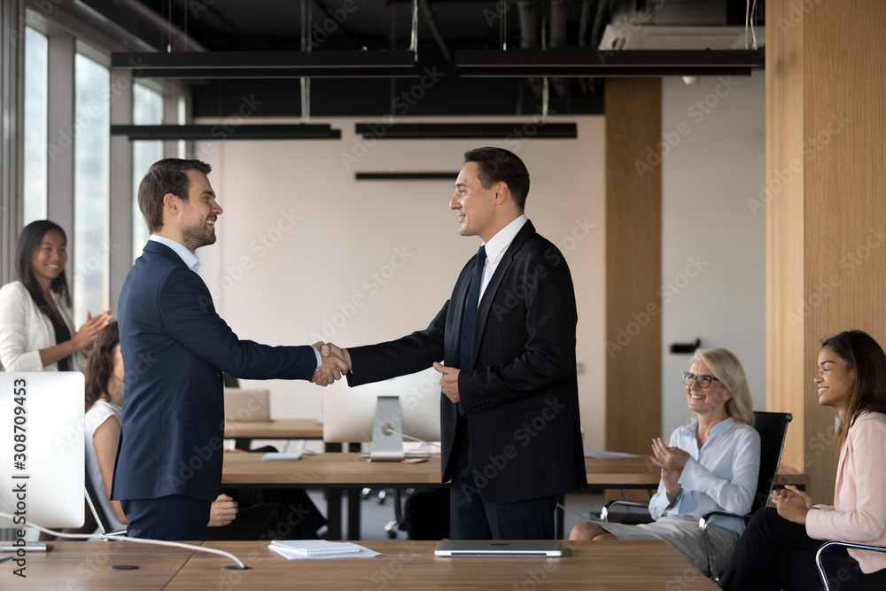 Executive manager shaking hand of successful employee at meeting Executive manager shaking hand of successful employee at meeting
