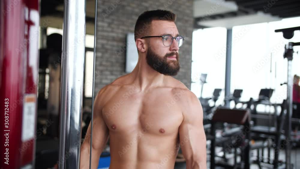 Shirtless athletic nerd man doing Outside grip cable biceps workout. Shirtless athletic nerd man doing Outside grip cable biceps workout.