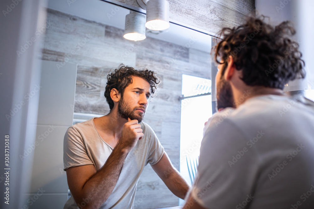 Morning hygiene, Handsome man in the bathroom looking in mirror ...