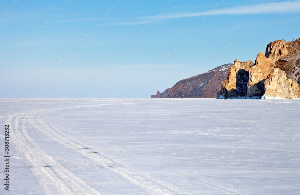 Winter Baikal Lake. The road through the snowy ice to the famous Khoboy cape past the Three Brothers rocks on a sunny February day. Winter ice travel concept