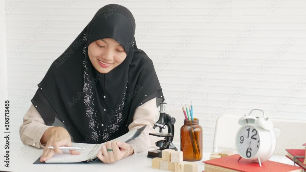 Young muslim girl work in the room with white background and some scientist decoration. Young muslim girl work in the room with white background and some scientist decoration.