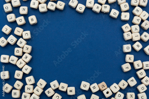 Wooden letter blocks over blue background, top view. Copy space.
