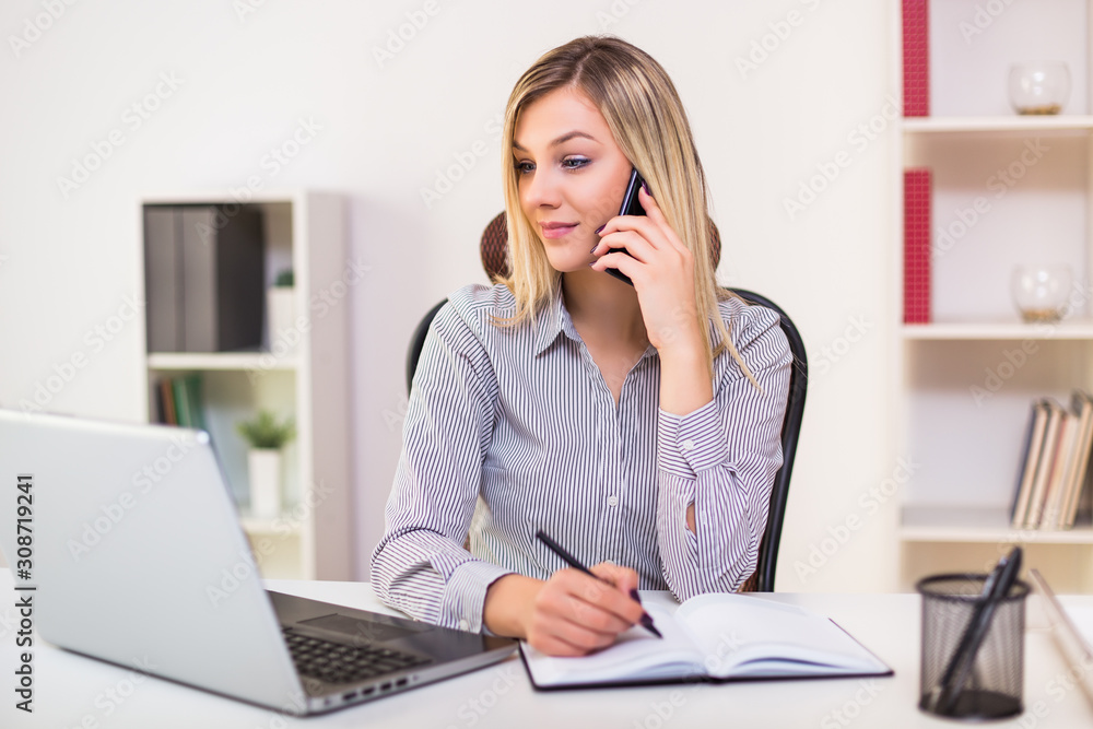 Businesswoman using mobile phone while working in her office. Businesswoman using mobile phone while working in her office.