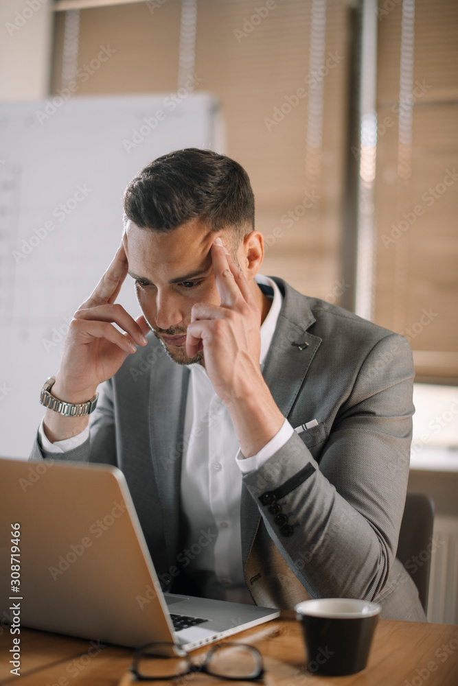Portrait of handsome businessman in office. Worried businessman working on laptop in office . Portrait of handsome businessman in office. Worried businessman working on laptop in office .