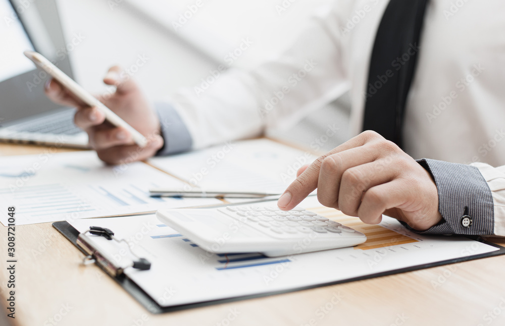 Business men use calculators to calculate the company's tax and revenue in the office, Financial and accounting banking concepts. Business men use calculators to calculate the company's tax and revenue in the office, Financial and accounting banking concepts.