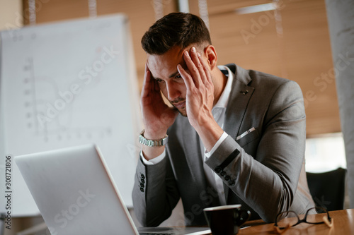 Portrait of handsome businessman in office. Worried businessman working on laptop in office .