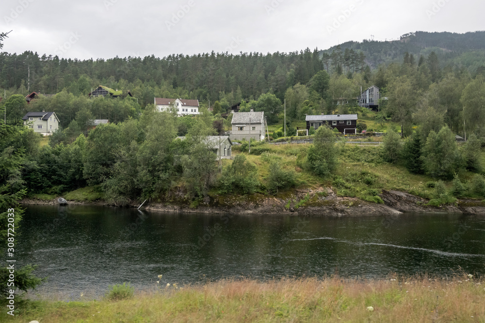 spaced out houses in wood on river waters, near Evanger , Norway