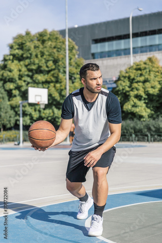 Basketball player carries in his right hand a basketball while playing a game on an outdoor court © Óscar