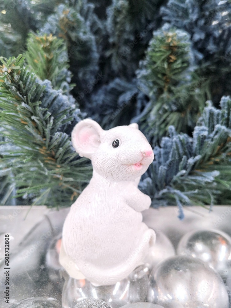Ceramic Funny mouse, symbol of 2020 year with artificial Christmas tree on background and shiny Christmas balls. Chinese zodiac - rat or mouse with selective focus. Vertical position 