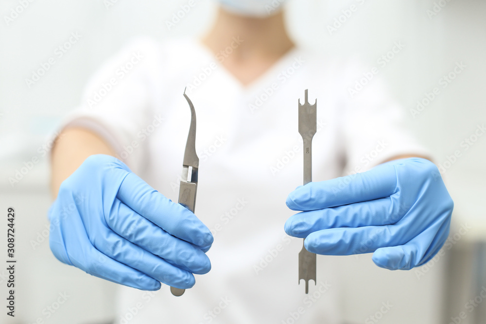 Closeup of hands of woman holding dentist tools in her hands. Selective focus Closeup of hands of woman holding dentist tools in her hands. Selective focus