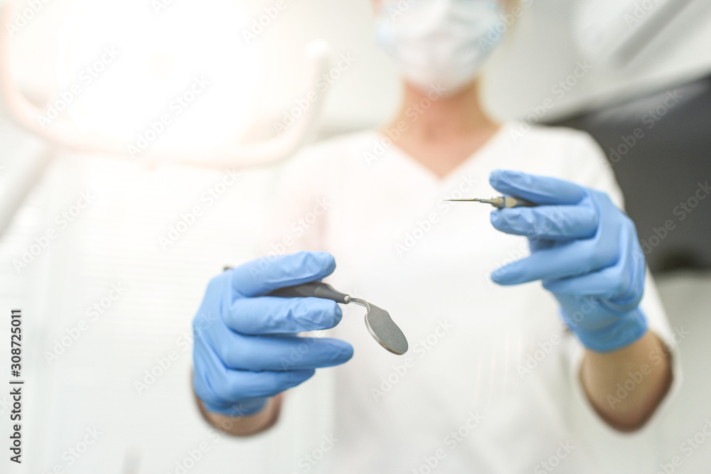 Closeup of dental instruments in hands of doctor. Selective focus Closeup of dental instruments in hands of doctor. Selective focus