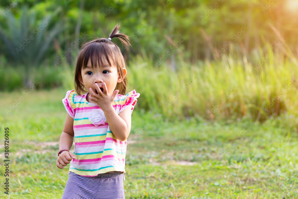 Portrait image of baby 1-2 years old. Asian child girl put her hands and in her mouth and biting her fingers at the playground. Personal hygiene and kid healthy concept. Portrait image of baby 1-2 years old. Asian child girl put her hands and in her mouth and biting her fingers at the playground. Personal hygiene and kid healthy concept.