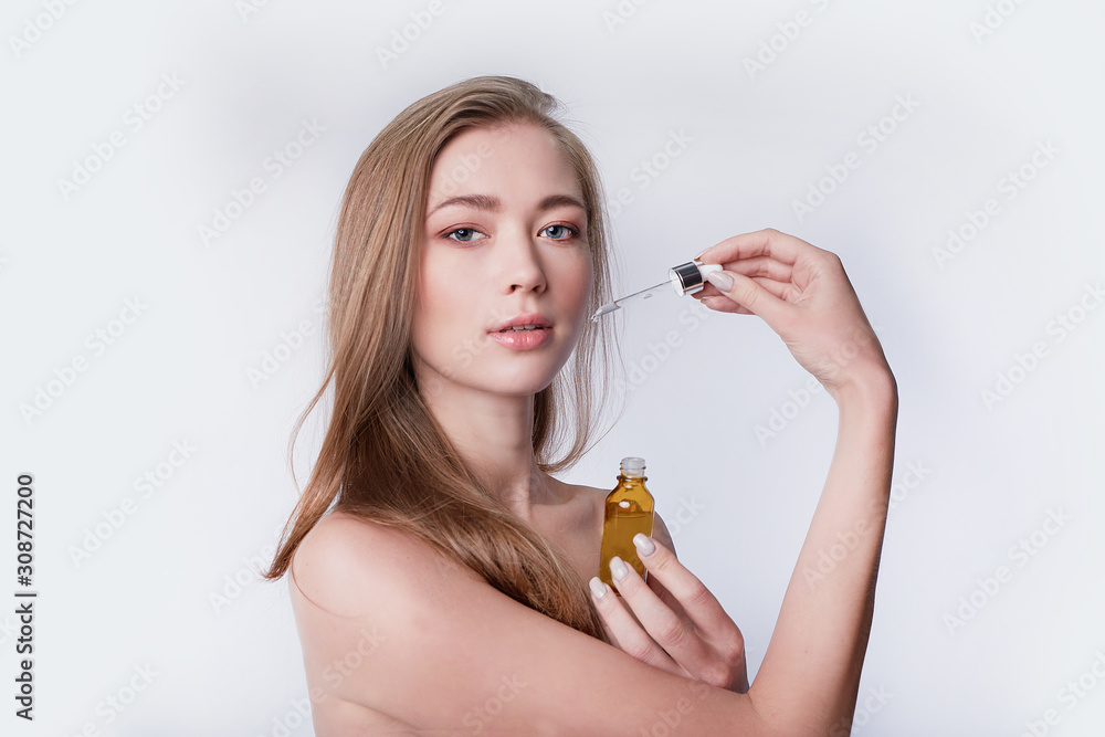 Fototapeta premium beautiful model applying a skin serum treatment on white. Spa, skincare and wellness. Close up, copyspace