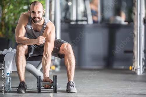 Muscular man practicing with dumbbells in fitness gym