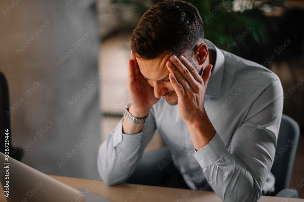 Portrait of handsome businessman in office. Tired businessman working on laptop in office . Portrait of handsome businessman in office. Tired businessman working on laptop in office .