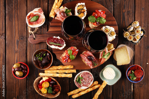 Appetizers table with italian antipasti snacks and wine in glasses. Brushetta or authentic traditional spanish tapas set, cheese variety