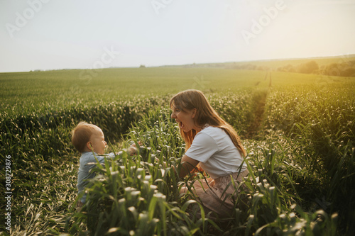 mother and child playing in the meadow on sunset