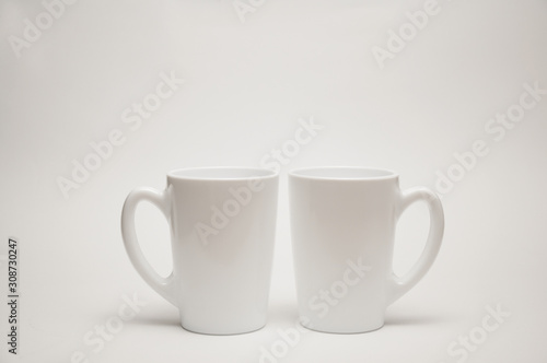 A white cup stands on a table on a white background.