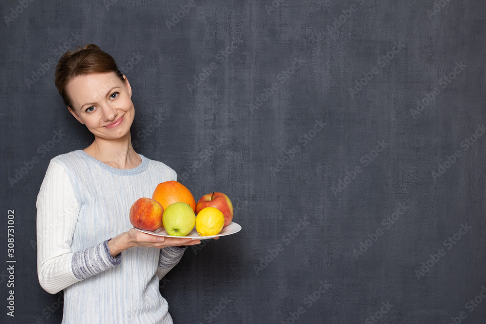Portrait of happy girl holding white plate with ripe appetising fruits Portrait of happy girl holding white plate with ripe appetising fruits