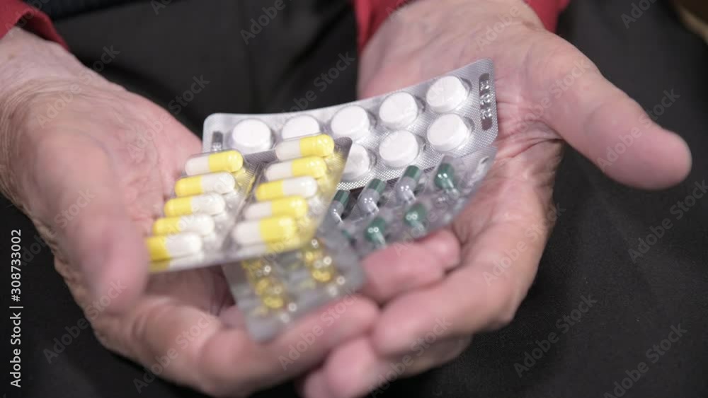 Closeup of a tablet on the hands of an old woman. The concept of choosing medication in old age Closeup of a tablet on the hands of an old woman. The concept of choosing medication in old age