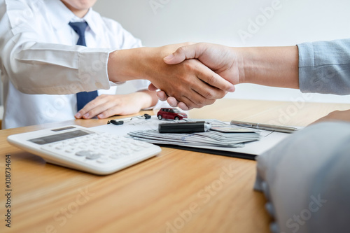 Car rental and Insurance concept, Young salesman shaking hands with customer after sign agreement contract with approved good deal for rent or purchase