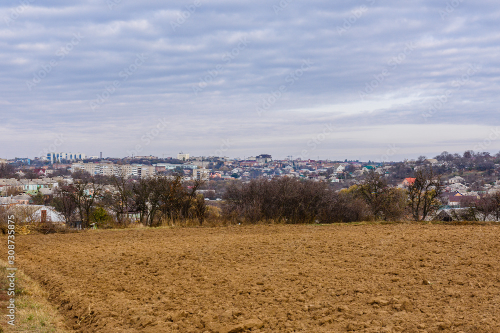 Plowed field at autumn. City Uman on a background. Ukraine