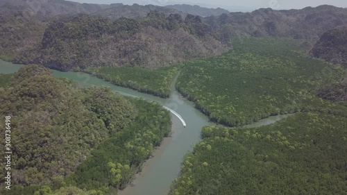 Aerial view of bay and river in Park Kilim Geoforest, Langkawi, Malaysia. Beautiful mountains, sea and trees around the river. Boat sailing on the river