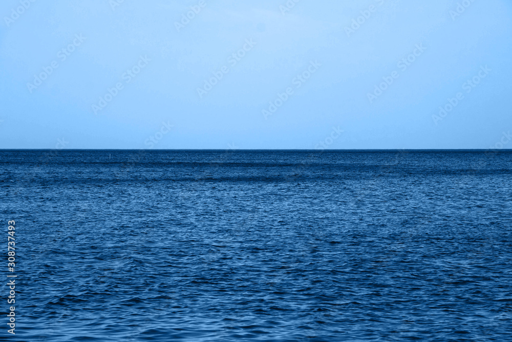 Calm Blue sea waves soft surface Ocean And Blue Sky in classic blue trendy color. background. Color of the year 2020.