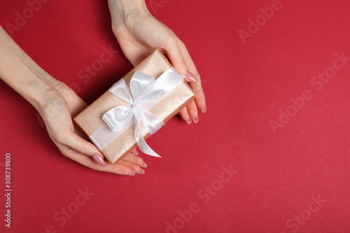 gift in female hands on a colored background top view.