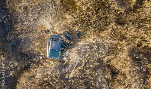 Crashed car in dry grass, abandoned.