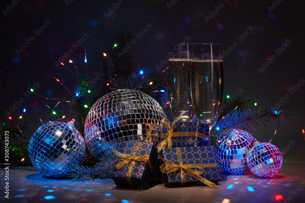 Champagne flutes, disco balls, gift boxes, fir branch, LED lights garland. New Year and Christmas