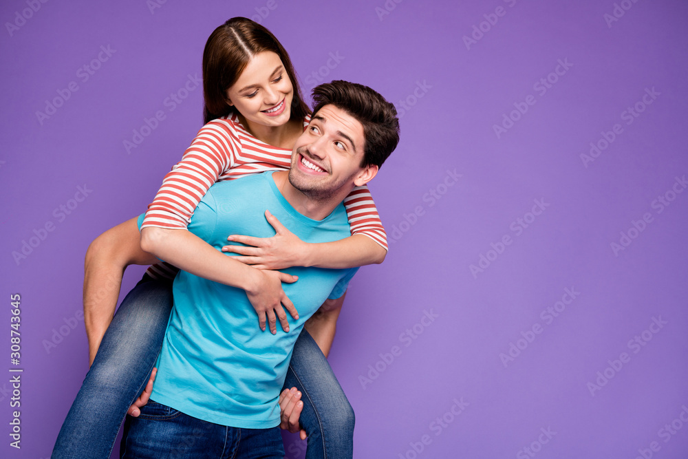 Naklejka premium Photo of two funky carefree people guy carrying lady piggyback look eyes cheerful free time adventures wear casual stylish blue striped t-shirts jeans isolated purple color background