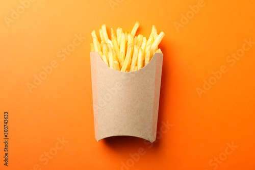 Εκτύπωση καμβά Slices of hot french fries in box on orange background, space for text