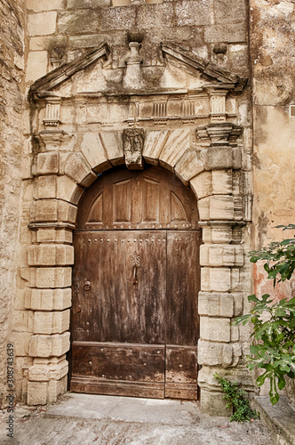 An old wood door in a majestic stone entry is closed in the village of Gordes in southern France.