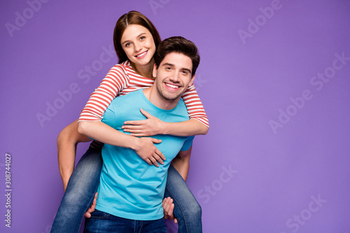 Photo of two charming carefree people guy carrying lady piggyback meet summer adventures together wear casual stylish blue striped t-shirts jeans isolated purple color background