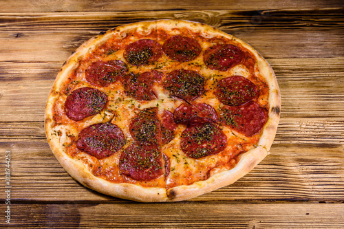 Pizza with salami sausage and parmesan cheese on a wooden table