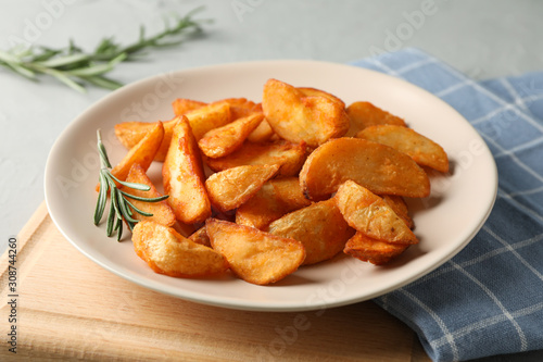 Plate with slices of baked potato wedges, napkin on gray background, space for text. Closeup