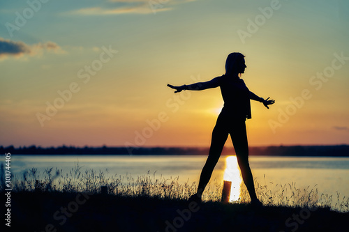 silhouette of a young woman at sunset. gymnastics, yoga, exercises, healthy lifestyle.